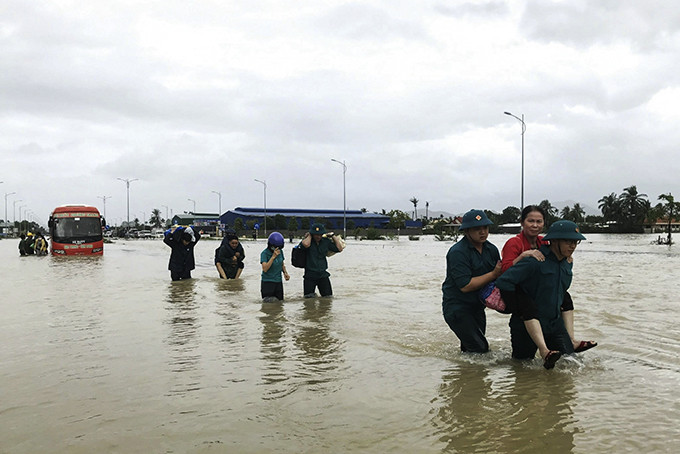 <p style= &quot;text-align: justify; &quot;>Lực lượng dân quân TP. Nha Trang giúp người dân di chuyển qua đoạn đường ngập lụt.</p>