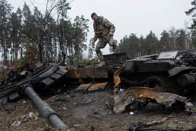 Binh sĩ Ukraine vượt qua một xác xe tăng ở Dmytrivka, ngoại ô Kiev ngày 2/4/2022. Ảnh: Getty Images