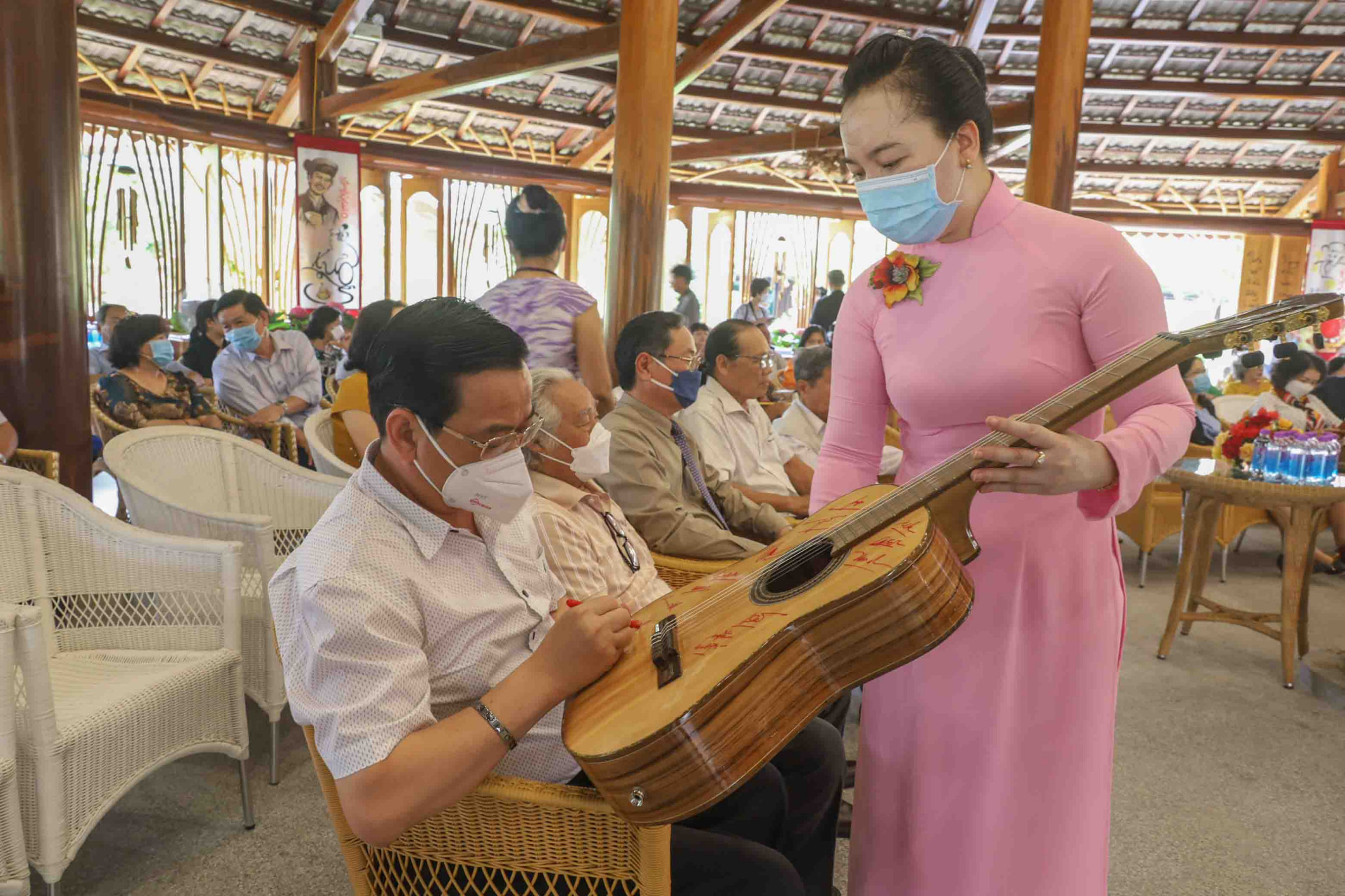Representatives sign the acoustic guitar made by artisans of Truong Son Craft Village during COVID-19