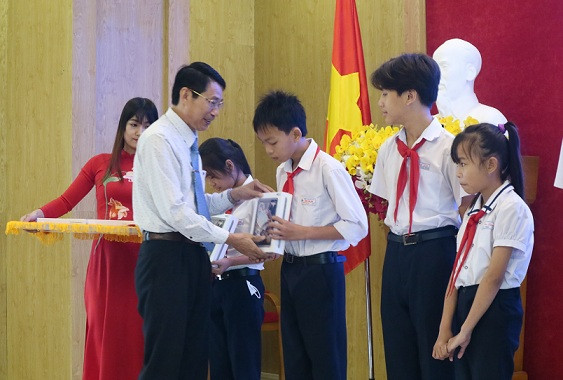 Ông Đinh Văn Thiệu trao máy tính bảng cho học sinh. 