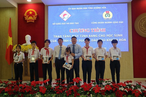 Ông Đinh Văn Thiệu và ông Võ Hoàn Hải - Giám đốc Sở Giáo dục và Đào tạo trao máy tính bảng cho các học sinh. 