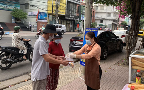 Bà Nguyễn Thị Cẩm Nhung - Chủ tịch UBMTTQ Việt Nam phường Vạn Thắng trao bánh mì cho người dân