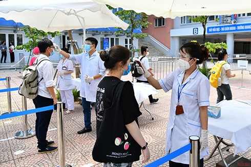 Lực lượng y tế đo thân nhiệt cho thí sinh tại điểm thi Trường THCS Phan Chu Trinh (Hà Nội) tại Kỳ thi tốt nghiệp THPT năm 2021. (Ảnh: Mỹ Hà)