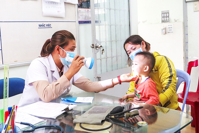 Cán  bộ   y  tế   Phòng  khám   Đa khoa  khu vực  Ninh Sim  khám bệnh  cho trẻ. 