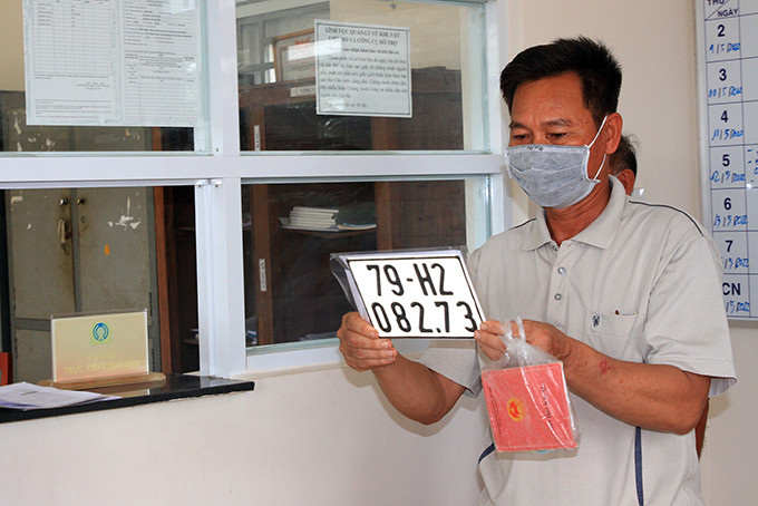 Ông Phạm Văn Chung vui vẻ nhận biển số cho chiếc xe mô tô mới mua của gia đình 
