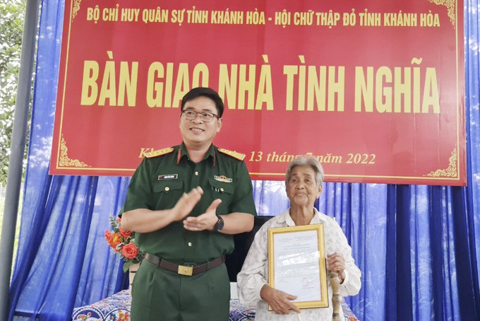 Đại tá Đinh Văn Hưng - Phó Chính ủy Bộ Chỉ huy Quân sự tỉnh trao quyết định tặng nhà tình nghĩa cho mẹ Nguyễn Thị Nhiễu.