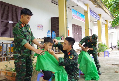 Các đoàn viên thanh niên cắt tóc cho các em thiếu nhi.