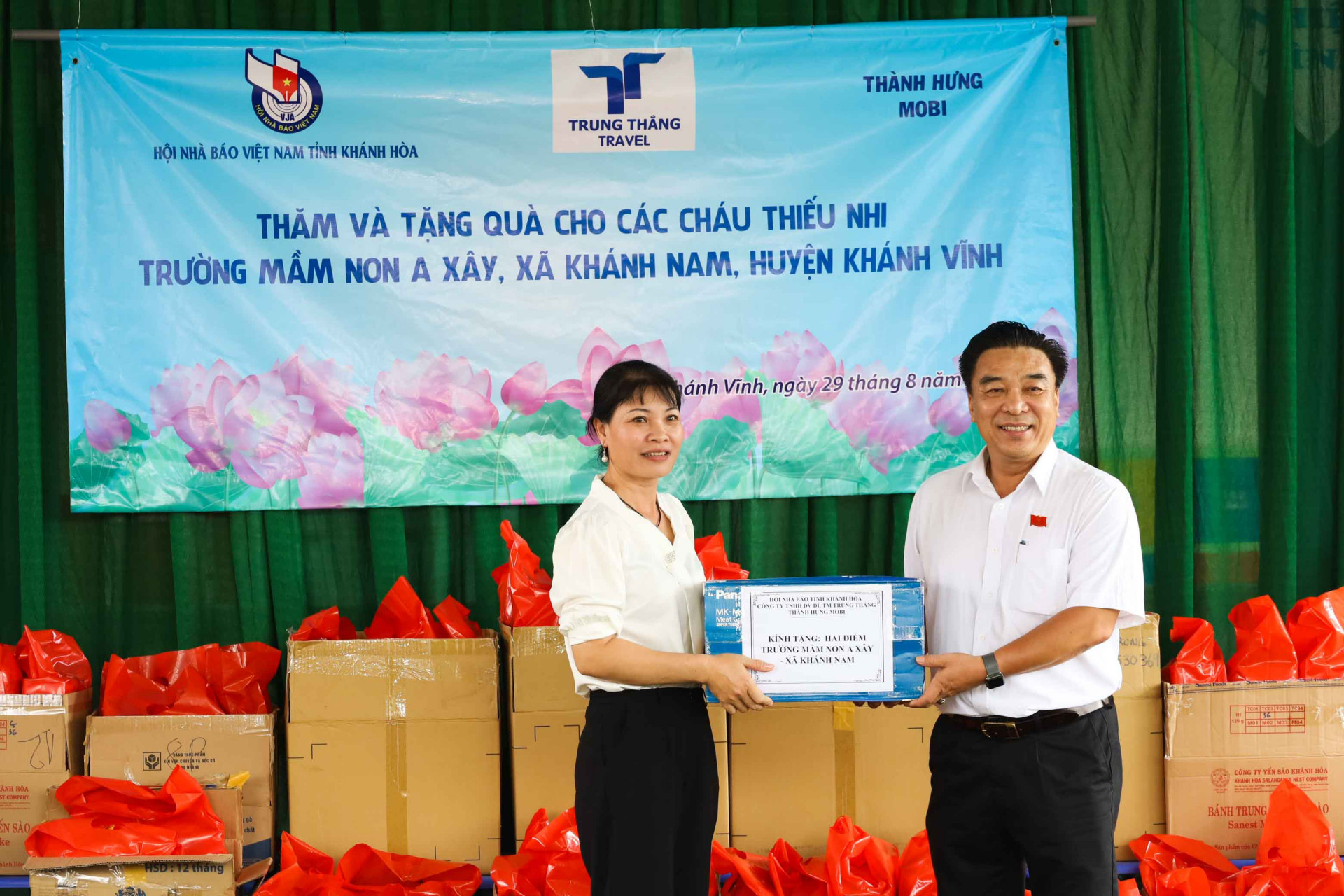 Lãnh đạo Hội Nhà báo tỉnh Khánh Hòa (bên phải) trao quà cho đại diện Trường Mầm non A Xây. 