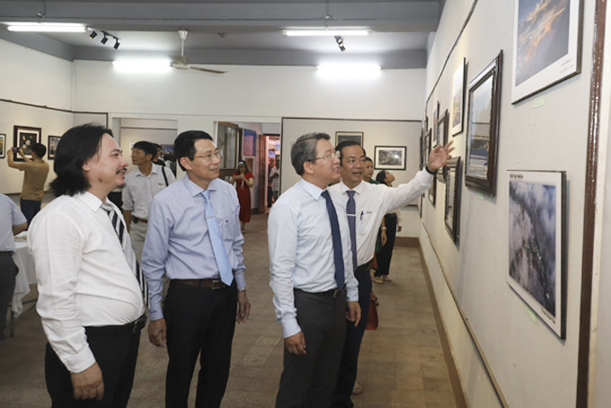 Ông Nguyễn Hải Ninh và các đại biểu xem các tác phẩm được giới thiệu tại triển lãm.  