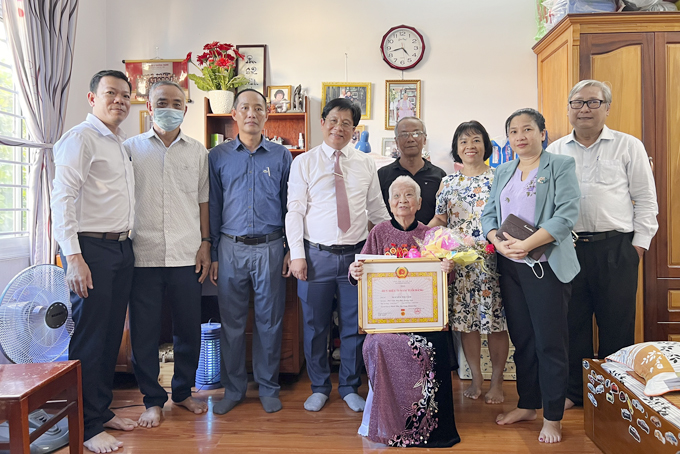 Đồng chí Hồ Văn Mừng trao Huy hiệu 75 năm tuổi Đảng  cho đảng viên lão thành Nguyễn Thị Tâm. 