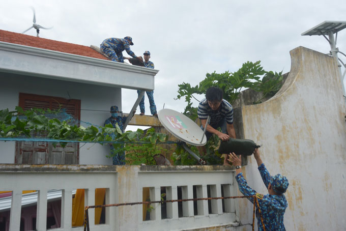 Cán bộ, chiến sĩ đảo Sinh Tồn giúp nhân dân chằng buộc mái nhà.