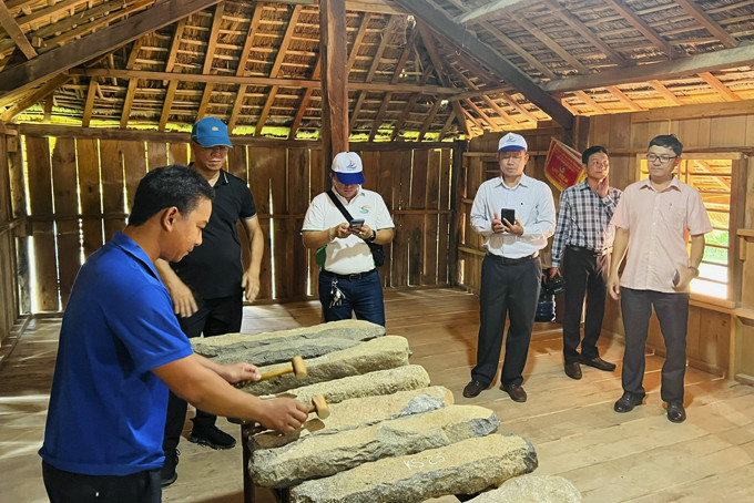 Đoàn khảo sát xem đồng bào Raglai đánh đàn đá  ở nhà dài thôn Hòn Dung, xã Sơn Hiệp.