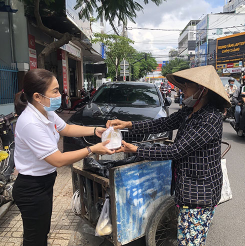 Bà Nguyễn Thị Cẩm Nhung - Chủ tịch UBMTTQ Việt Nam phường Vạn Thắng trao suất cơm cho một người lao động nghèo