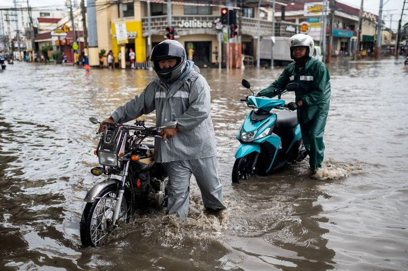 Người dân dắt xe đi qua tuyến đường bị ngập tại vùng thủ đô Manila, Philippines, ngày 30/10. (Ảnh: Reuters)