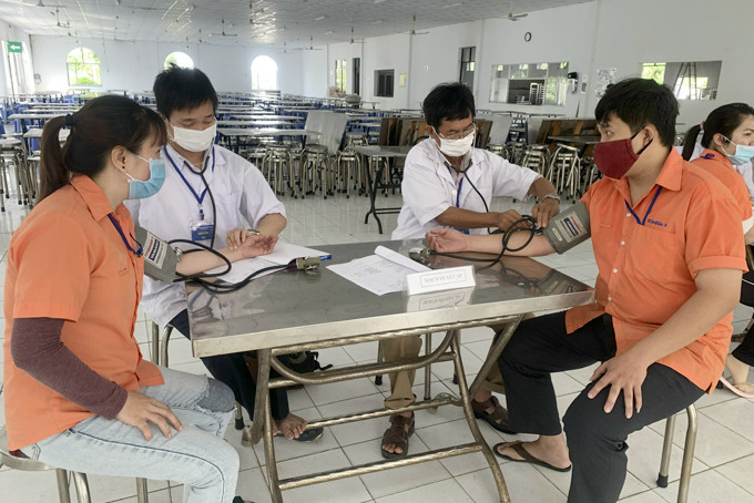 Cán bộ Trung tâm Kiểm soát bệnh tật tỉnh kiểm tra sức khỏe  cho công nhân ở Khu Công nghiệp Suối Dầu.