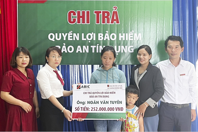 Đại diện ABIC Khánh Hòa trao bảng tượng trưng  số tiền chi trả bảo hiểm cho gia đình ông Tuyên.