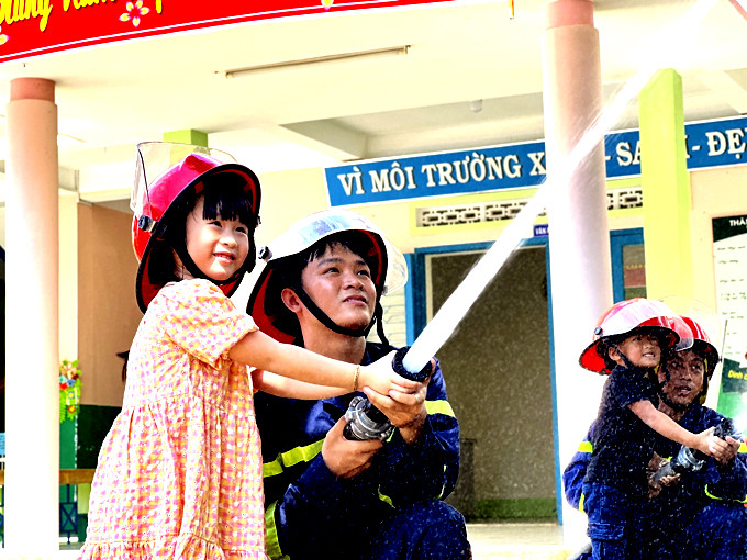 Các bé Trường Mầm non Bình Minh (thị trấn Vạn Giã, huyện Vạn Ninh) thực hành với lăng chữa cháy.