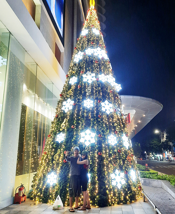 A couple posing in front of Vincom Plaza on Le Thanh Ton Street