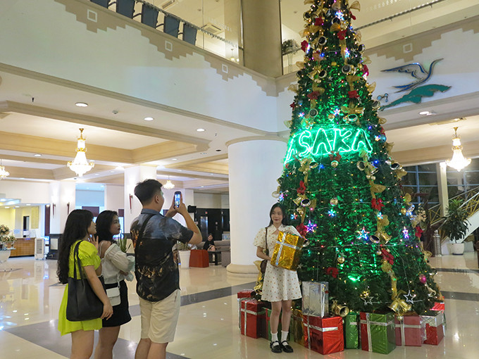 Young people have their photo taken with Christmas decorations at Yasaka Saigon Nha Trang Hotel