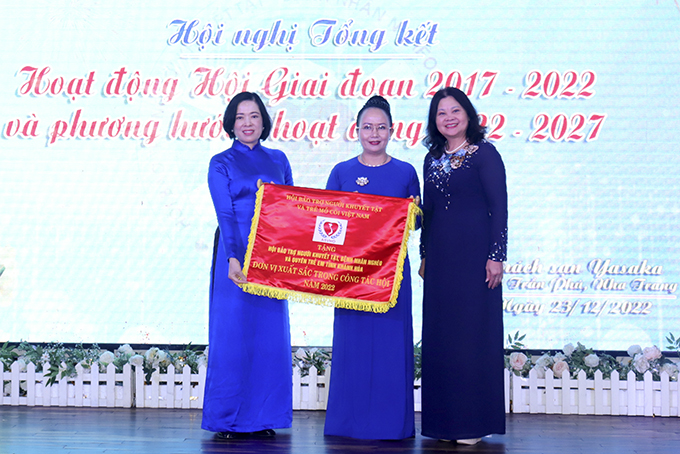 Bà Trần Thị Dung - Phó Chủ tịch Hội Bảo trợ Người khuyết tật và Trẻ mồ côi Việt Nam (bìa phải) trao cờ cho Hội Bảo trợ Người khuyết tật, Bệnh nhân nghèo và Quyền trẻ em tỉnh.