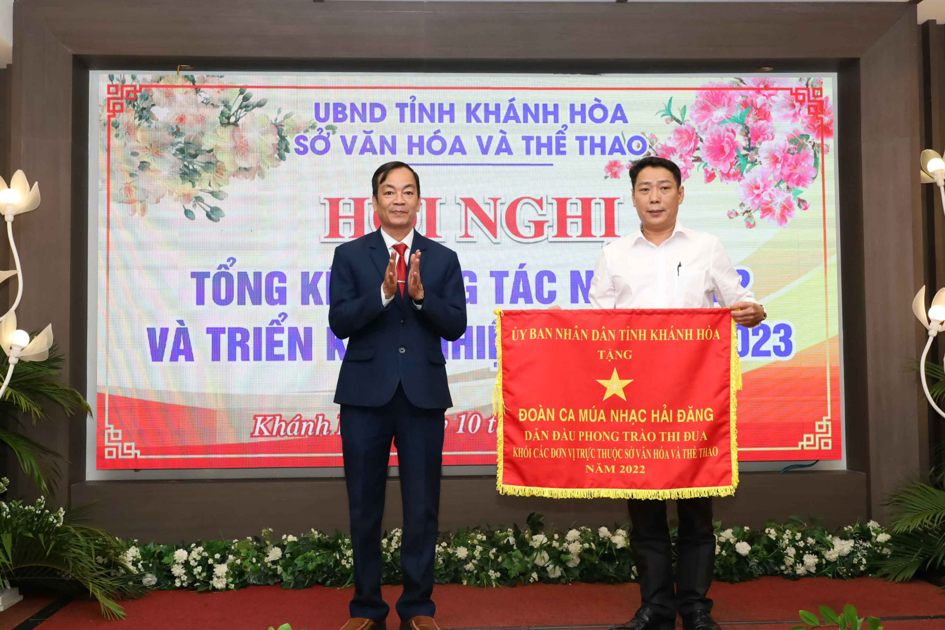 Ông Nguyễn Văn Thiện – Giám đốc Sở VHTT Khánh Hòa trao cờ thi đua của UBND tỉnh Khánh Hòa cho đại diện Đoàn ca múa nhạc Hải Đăng. 