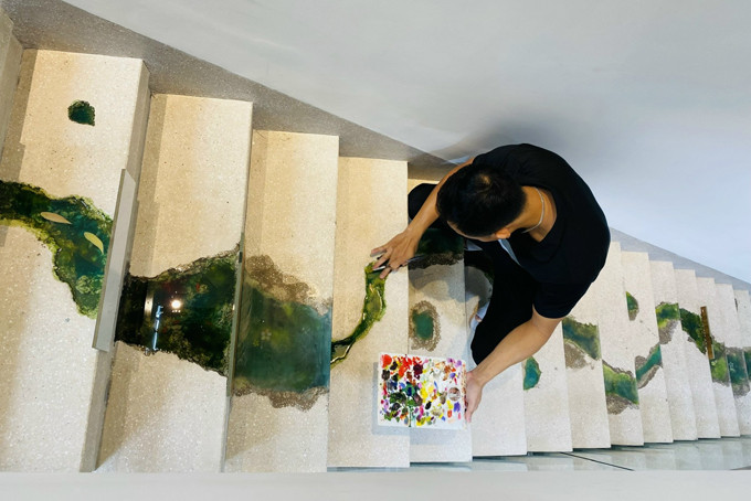 l Anh Lê Phạm  Chiến Thắng đang hoàn thiện bức tranh dòng suối với đàn cá bơi ngược ở cầu thang.