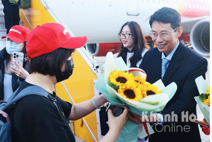 Ông Đinh Văn Thiệu tặng hoa cho khách du lịch đầu tiên xuống sân bay.