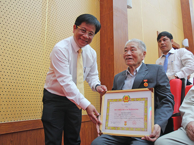 Ông Hồ Văn Mừng trao Huy hiệu 60 năm tuổi Đảng tại chỗ ngồi cho 1 đảng viên yếu mệt.