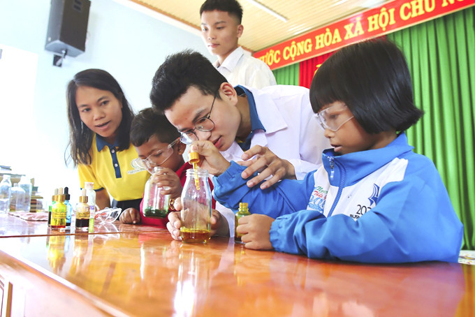 Cô Yến và sinh viên Trường Đại học Nha Trang hướng dẫn các em nhỏ ở Khánh Sơn làm thí nghiệm khoa học.