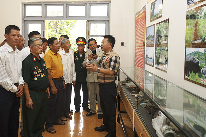 Ông Lê Xuân Thơm (bìa phải) giới thiệu cho các cựu chiến binh về căn cứ cách mạng Đồng Bò.