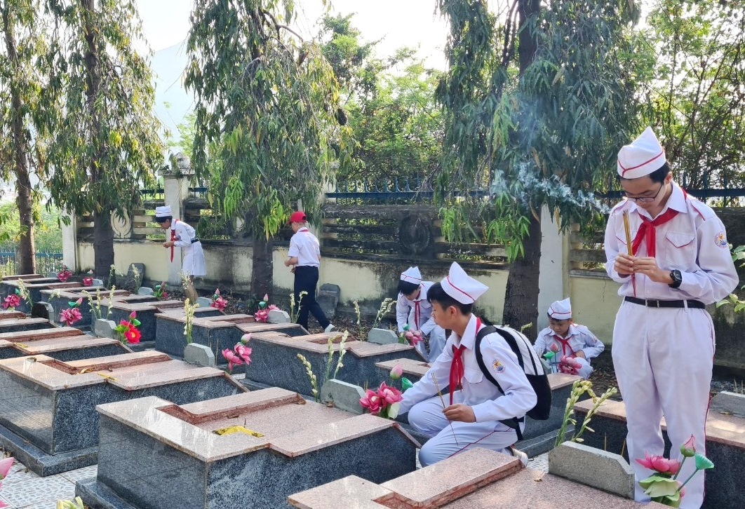 Các học sinh thắp hương tại phần mộ các anh hùng, liệt sĩ. 